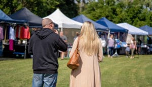 Crowd of people on grassy lawn with vendor tents at annual wine festival