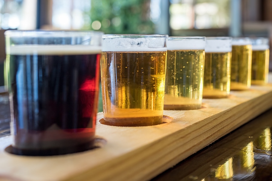 Beer samplers in small glasses individually placed in holes fashioned into a unique wooden tray at breweries and wineries.